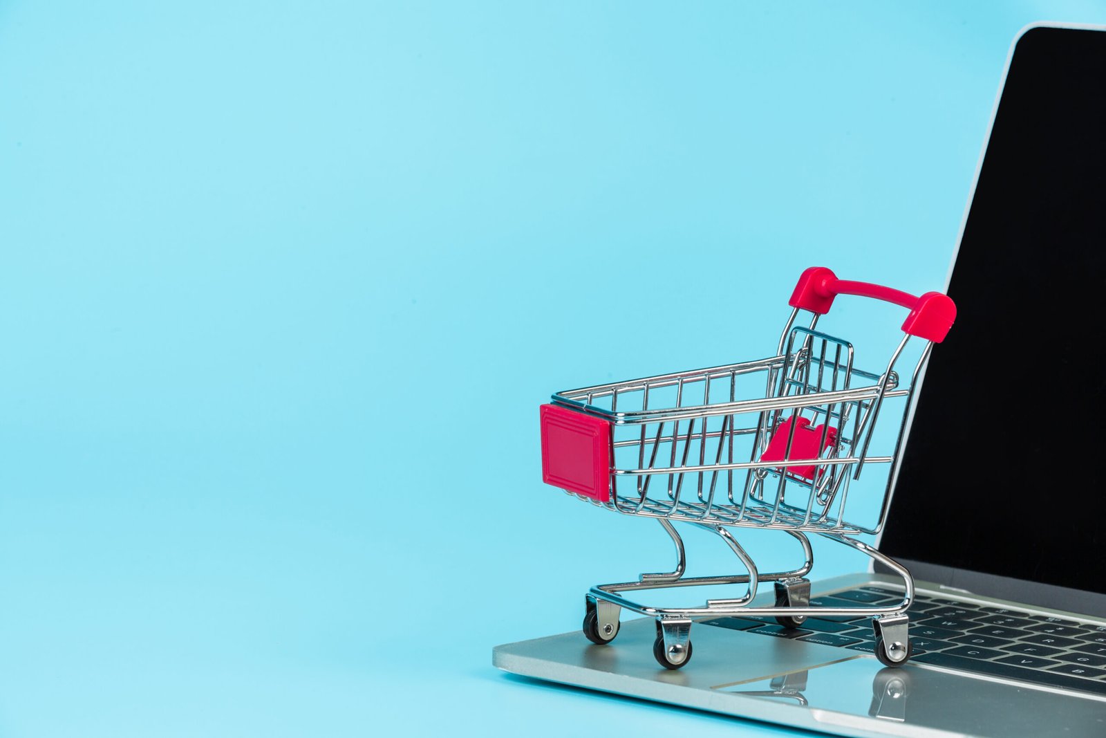 Online shopping concept, a shopping cart placed alongside a notebook on a blue background.